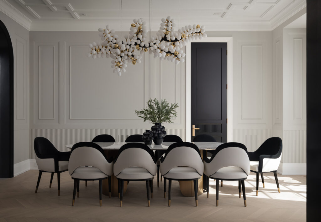 A sophisticated dining room with monochrome chairs and an artistic chandelier, professionally photographed by a Toronto interior photographer highlighting balance and texture.